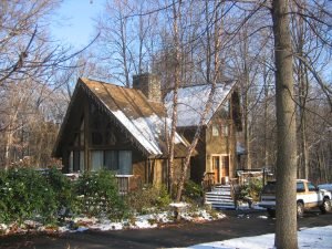 Angled view of Riverside kit home with A-frame design and snowy driveway