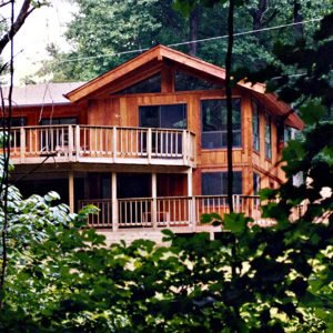 Lovington kit home with large elevated deck and wood siding surrounded by trees