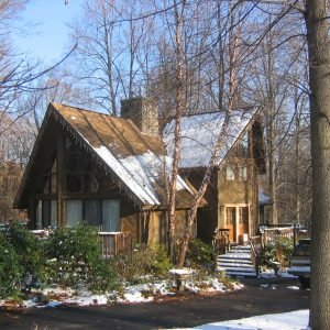 Angled view of Riverside kit home with A-frame design and snowy driveway