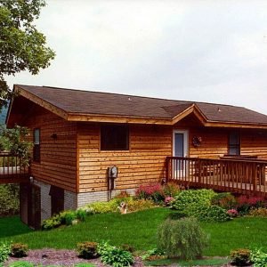 Big Pine kit home with wood siding, elevated deck, and landscaped front yard